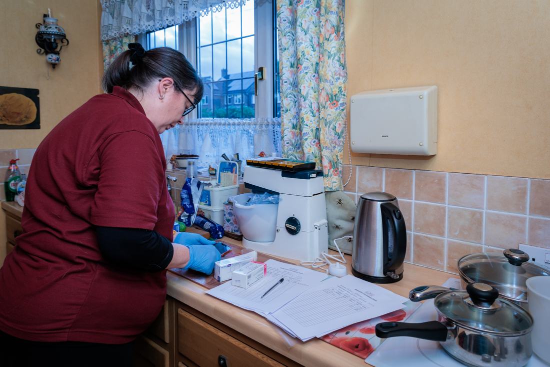 A carer working through care notes in a client’s kitchen