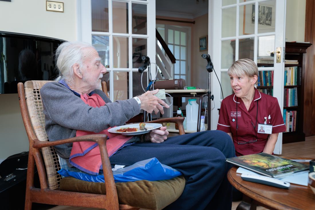 A carer sitting with a client at home