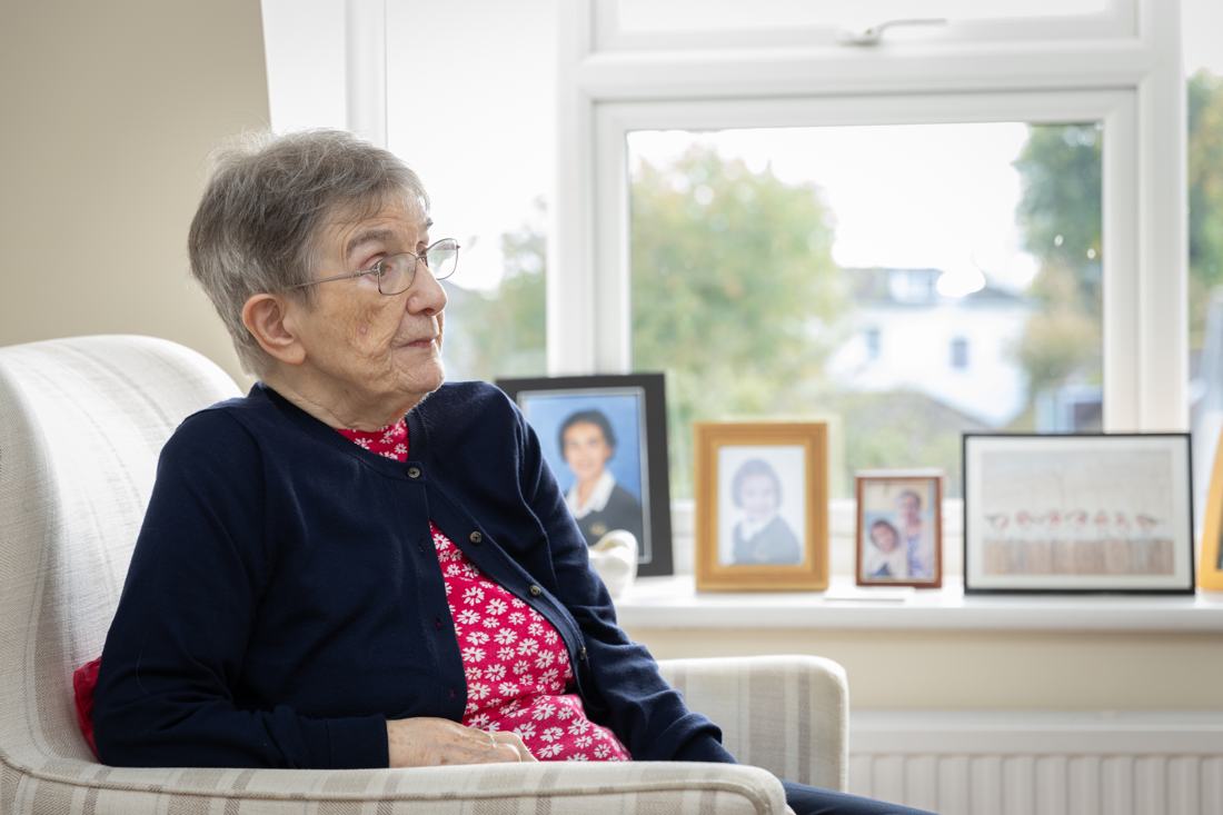 A client sitting in her armchair by the window, surrounded by family photos