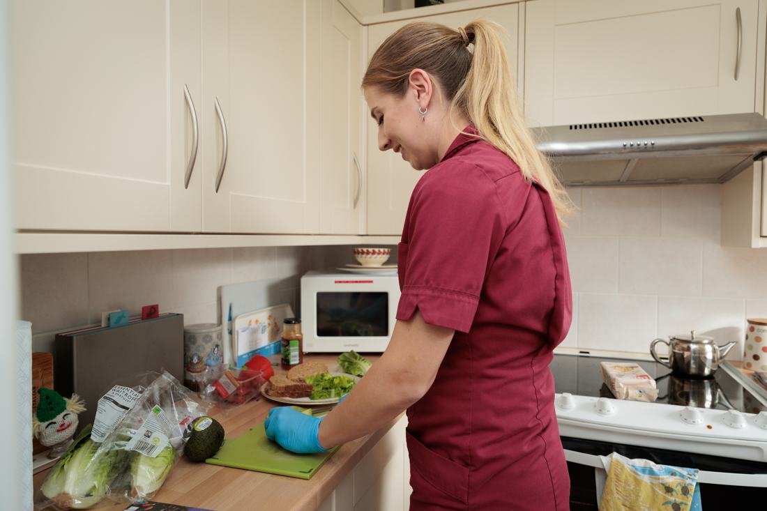 A carer preparing a meal in a client’s kitchen